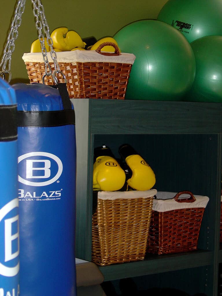 Single blue Balazs heavy bag hanging beside kettlebells and storage baskets in a fitness studio