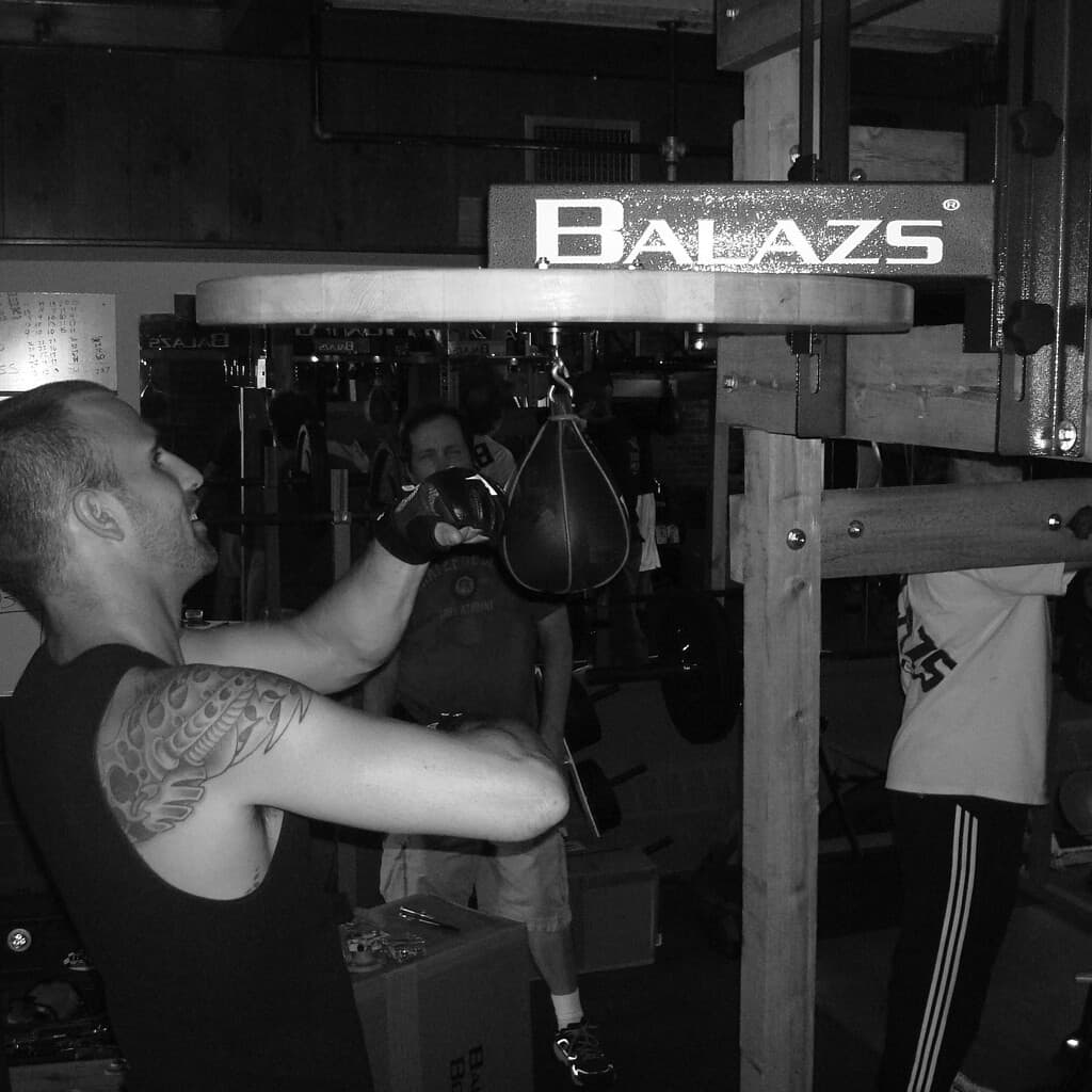 Black and white photograph of a boxer working a speed bag on a Balazs speed bag platform