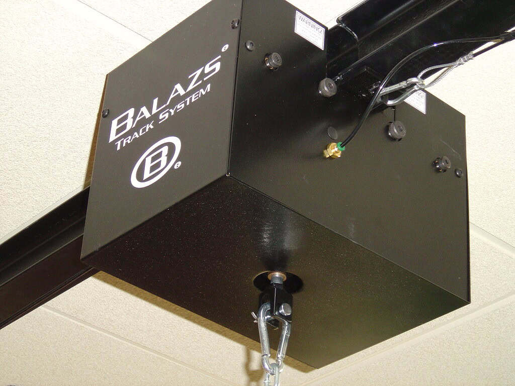 Close-up of a Balazs Track System trolley mounted under a ceiling track