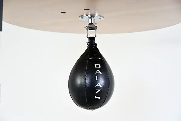 Black Balazs Lazer 10 x 7 inch medium speed bag, Balazs-logo view, mounted beneath a wooden platform