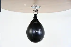 Black Balazs Lazer 10 x 7 inch medium speed bag, Lazer-logo view, mounted beneath a wooden platform