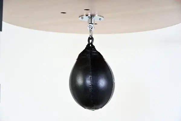 Black Balazs Lazer 10 x 7 inch medium speed bag, side view, mounted beneath a wooden platform