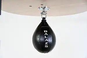 Black Balazs Lazer 11 x 8 inch large speed bag, Balazs-logo view, mounted beneath a wooden platform