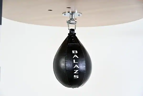 Black Balazs Lazer 11 x 8 inch large speed bag, Balazs-logo view, mounted beneath a wooden platform