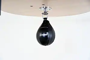 Black Balazs Lazer 8 x 5 inch peanut speed bag, Lazer-logo view, mounted beneath a wooden platform