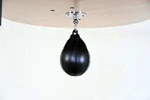 Black Balazs Lazer 8 x 5 inch peanut speed bag, side view, mounted beneath a wooden platform