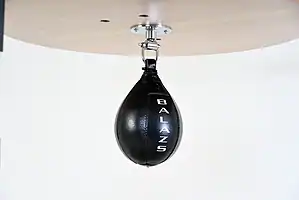 Black Balazs Lazer 9 x 6 inch small speed bag, Balazs-logo view, mounted beneath a wooden platform